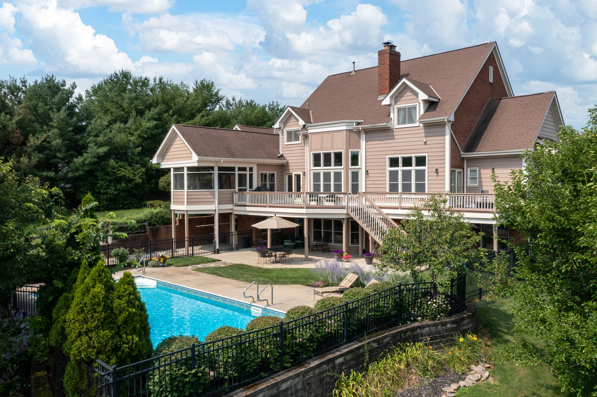 Elevated view of a home with a raised deck and surrounding trees