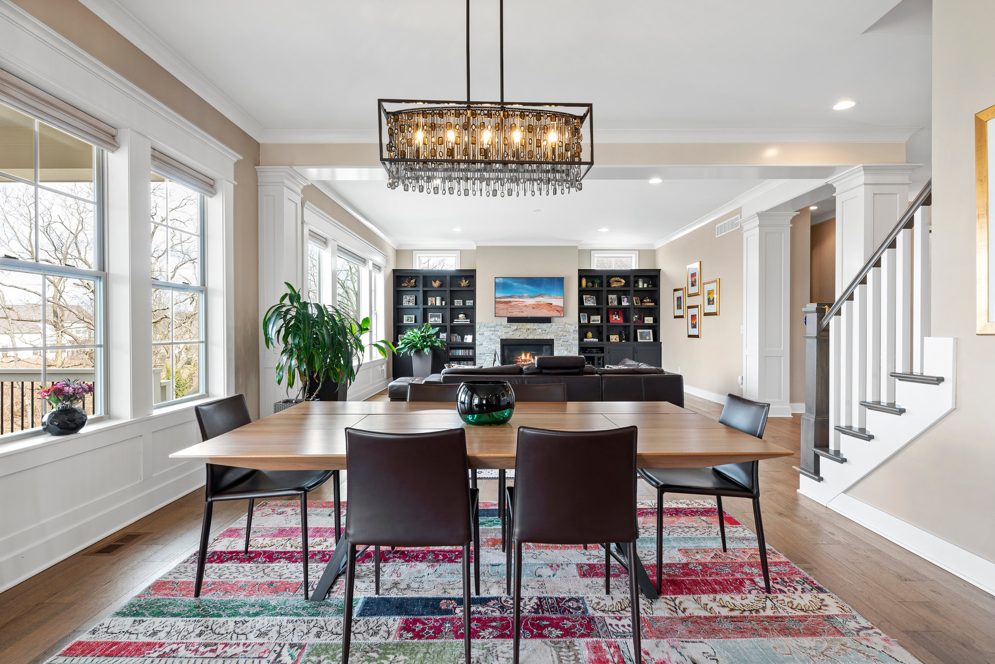Dining area with table, chairs and framed art beside a staircase