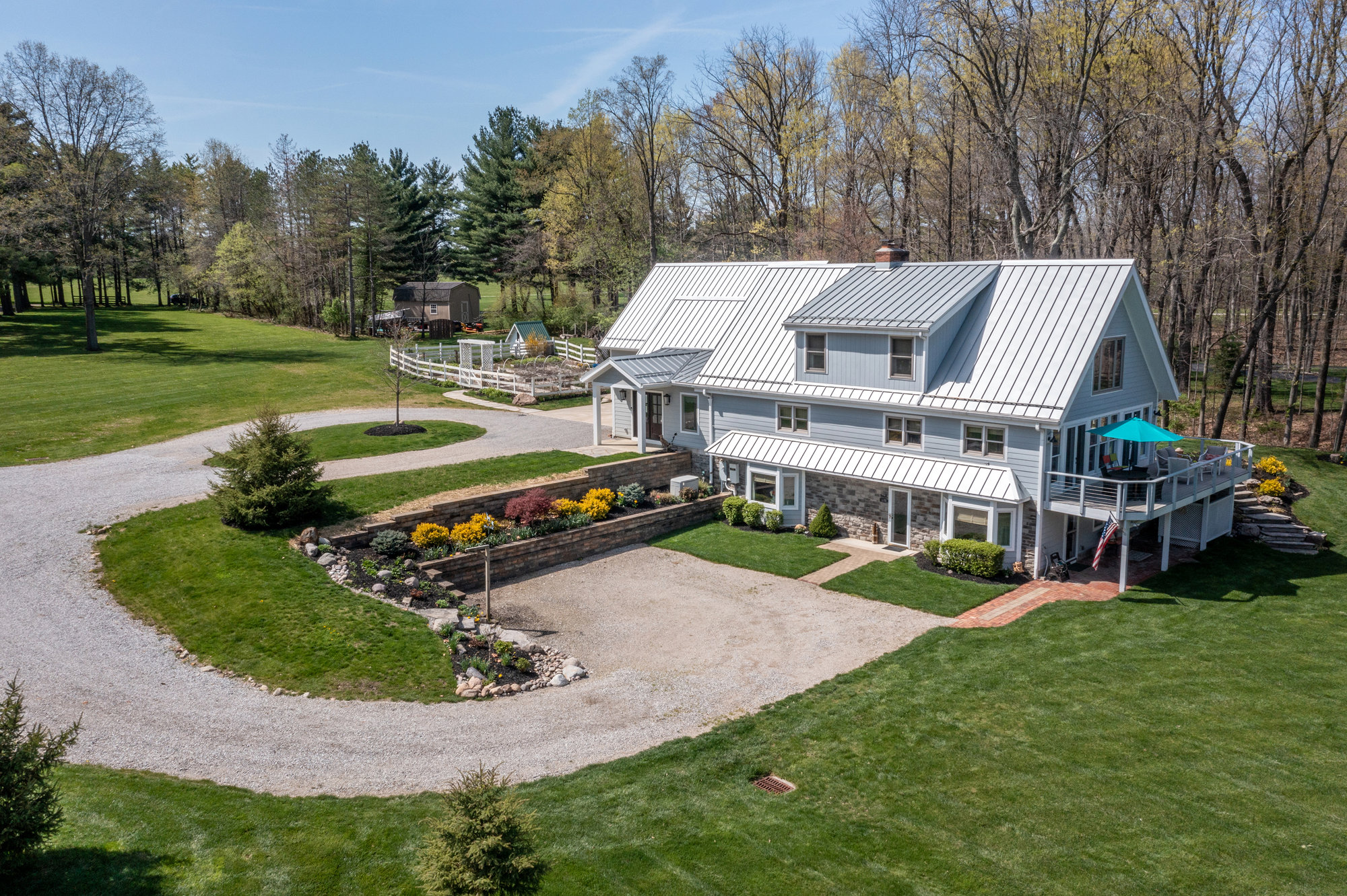 Aerial view of a home with a circular driveway and landscaped grounds