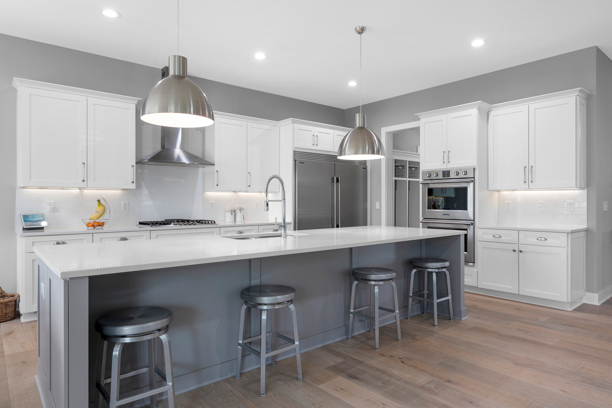 Modern kitchen with white cabinetry, a grey island and stainless range