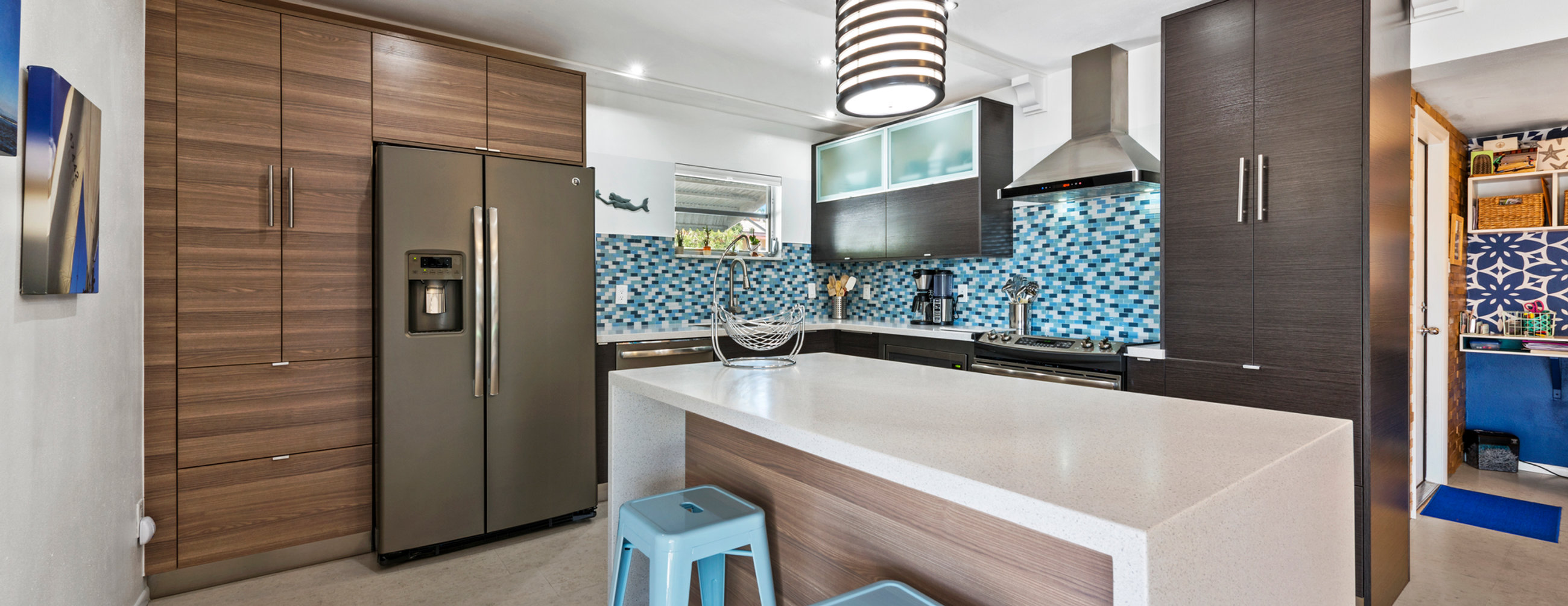 Wide panoramic view of a contemporary kitchen with wood cabinetry and a white island