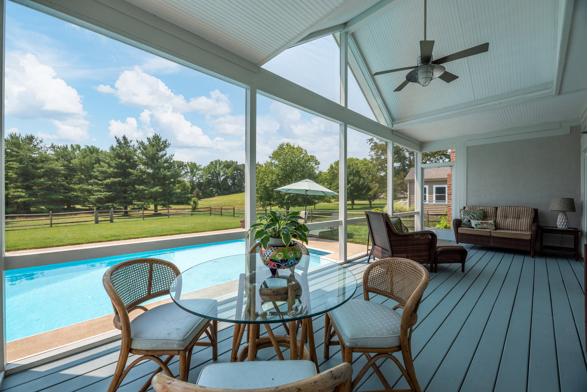 Screened patio seating overlooking a swimming pool and lawn