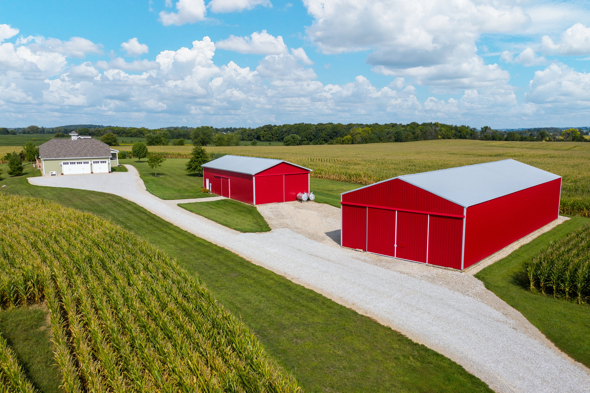 Aerial view of red farm buildings, open land and tree line