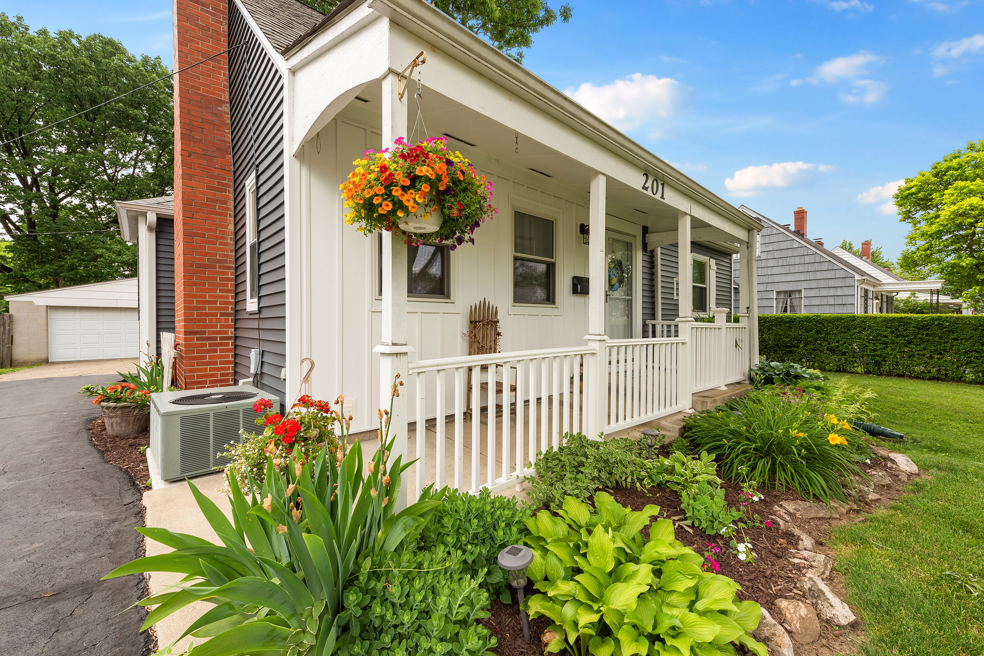 Home entrance with flower baskets and a white picket fence